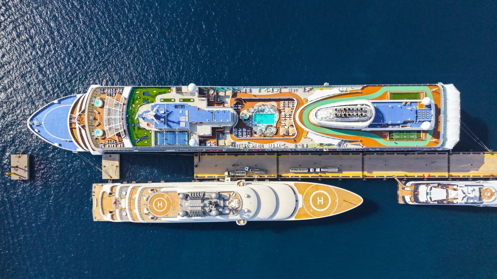 Aerial view of two cruise ships at a pier showing their pools and waterslides: the best family cruise lines compared